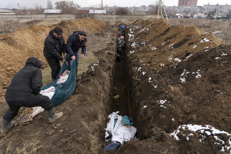 Los cadáveres son colocados en una fosa común en las afueras de Mariupol, Ucrania, el miércoles 9 de marzo de 2022, ya que la gente no puede enterrar a sus muertos debido a los intensos bombardeos de las fuerzas rusas. (Foto AP/Mstyslav Chernov)