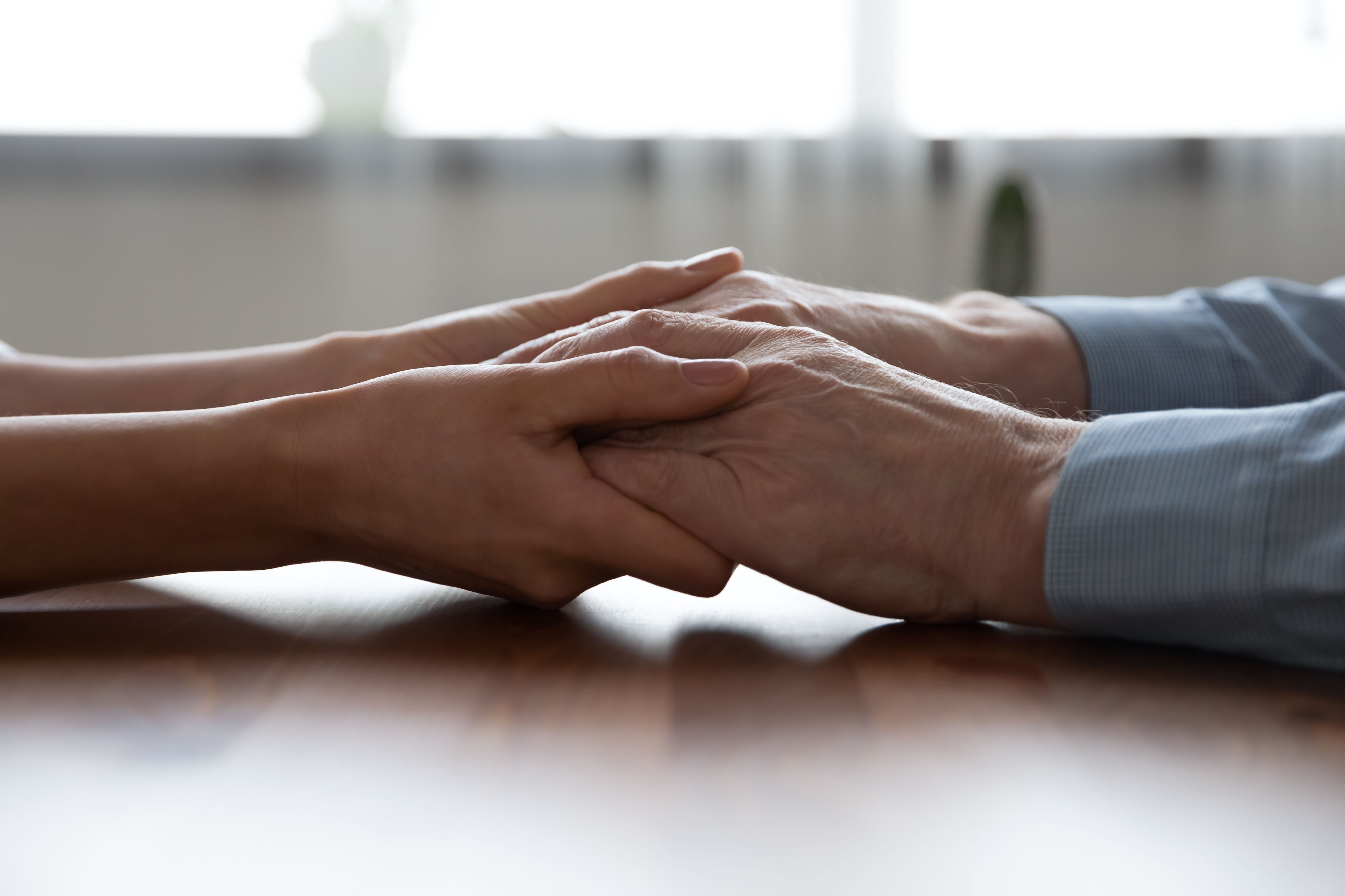 Young woman holding older man hands, close up view