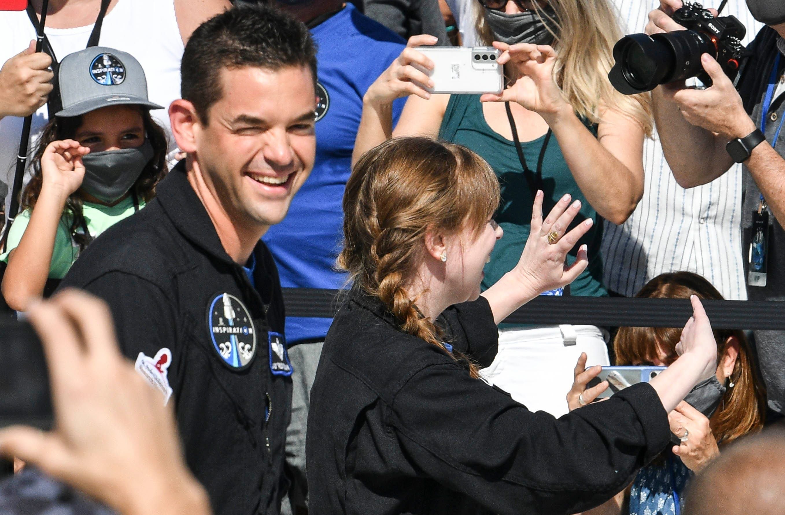 Jared Isaacman and Hayley Arceneaux wave to the crowd as they and the rest of the Inspiration4 crew head to the launch pad