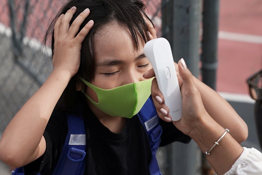 A child has his temperature taken before attending the first day of grade 2