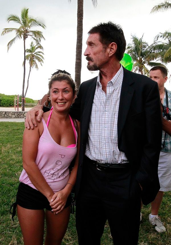 Computer software pioneer McAfee poses with a tourist after speaking with reporters outside his hotel in Miami Beach