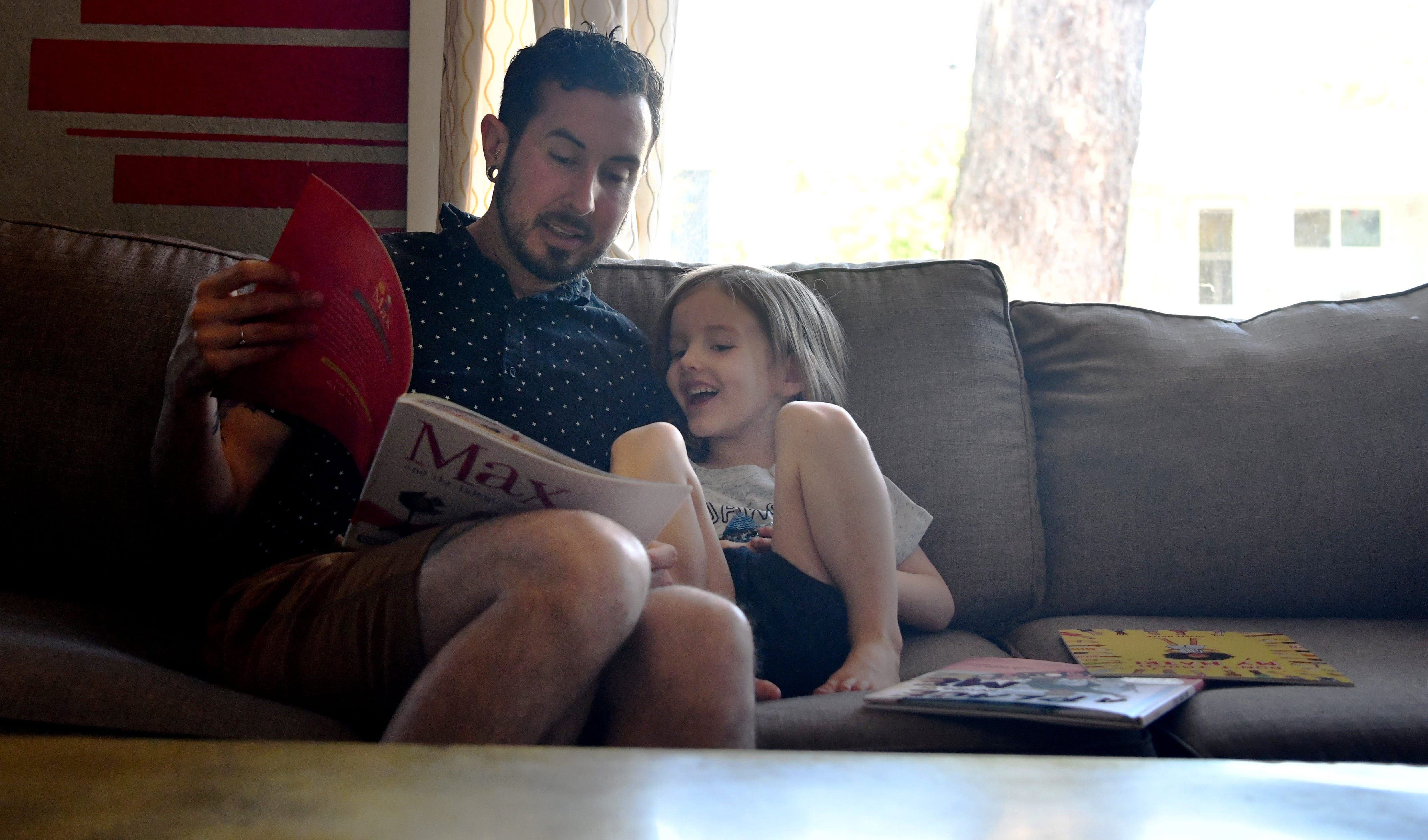 May 16, 2021; Portland, Oregon, USA; Trystan Reese and his son Leo, 3, read books together at home. Trystan is a transgender man