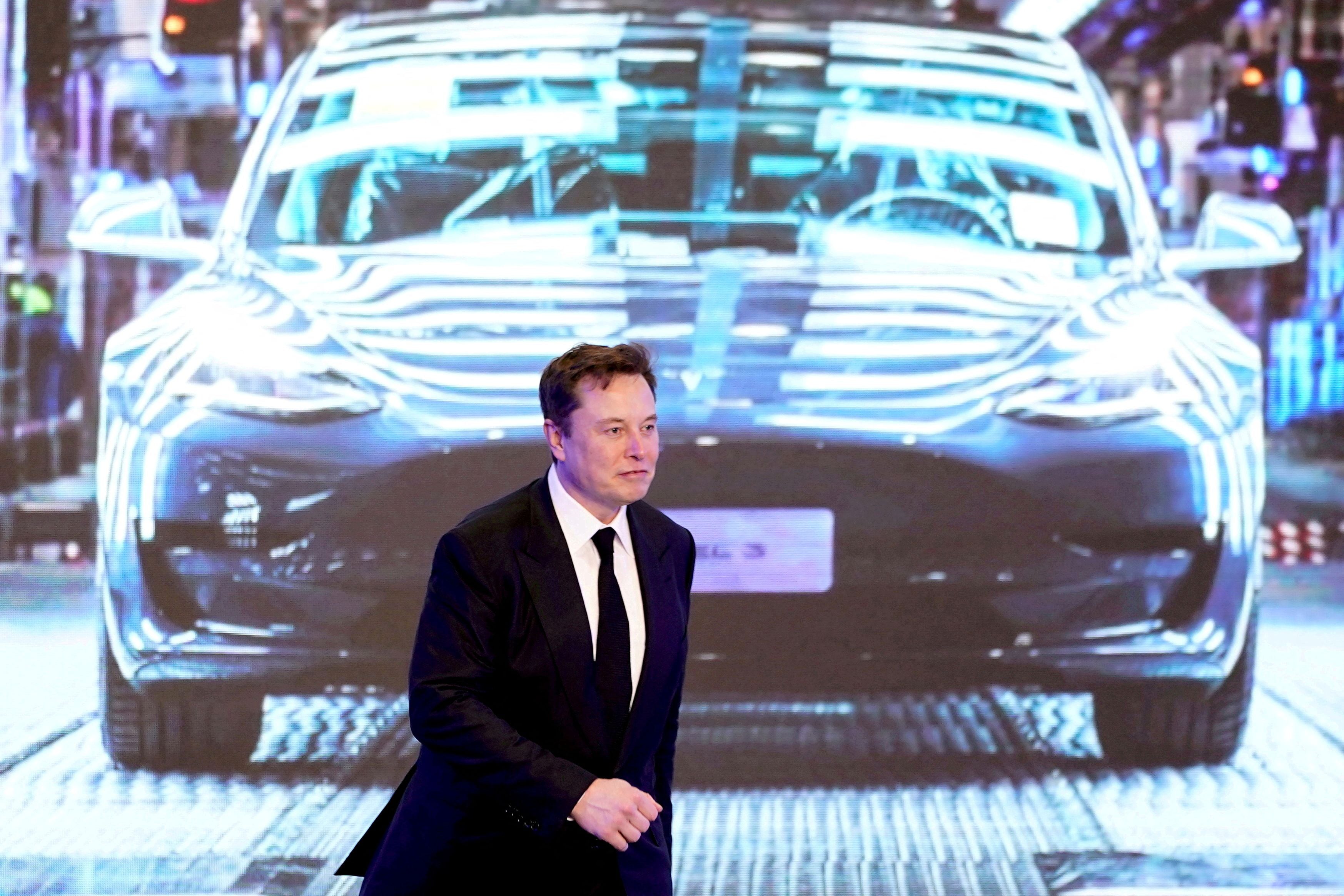 FILE PHOTO: Tesla Inc CEO Elon Musk walks next to a screen showing an image of Tesla Model 3 car during an opening ceremony for Tesla China-made Model Y program in Shanghai