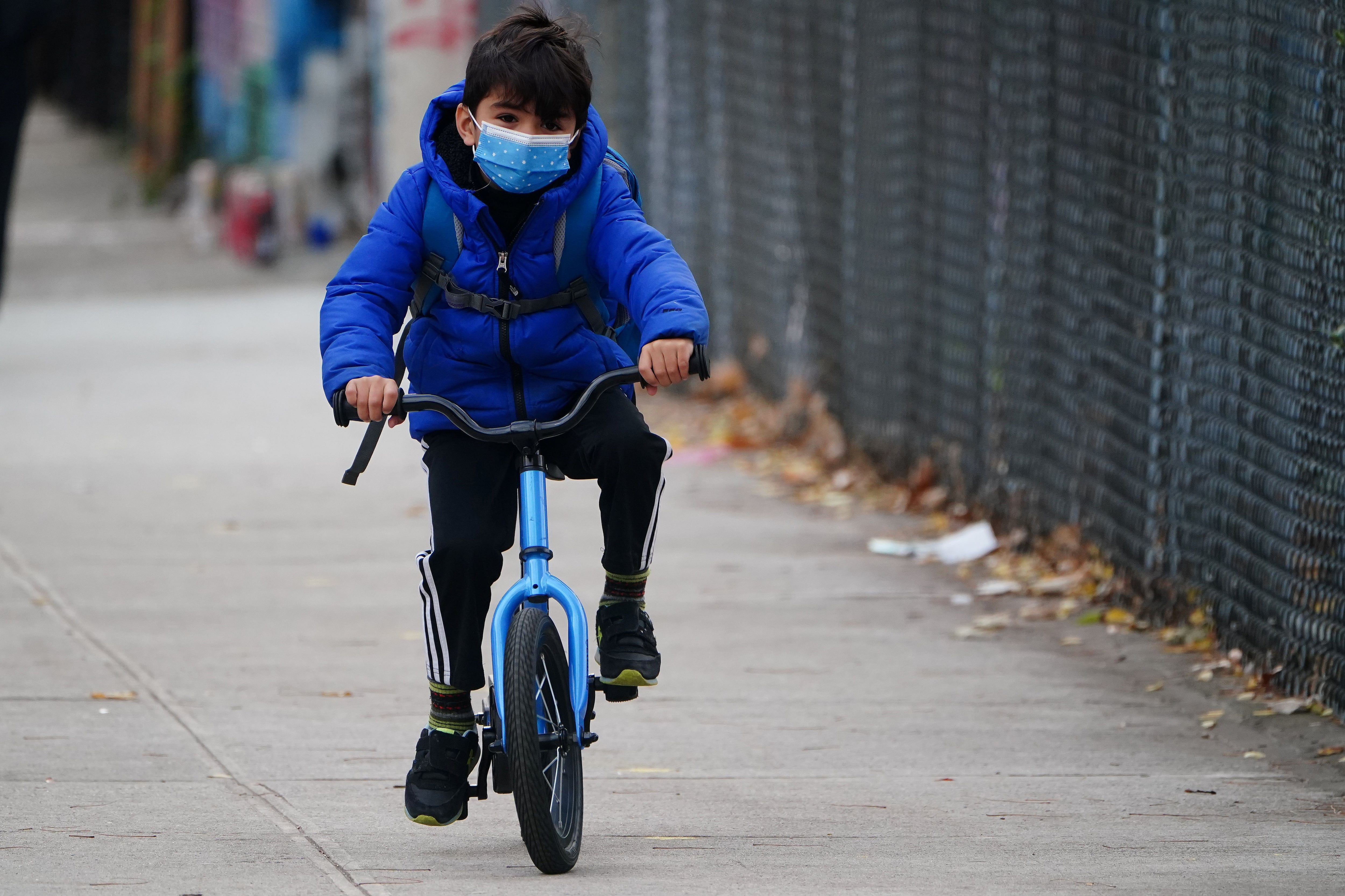 A child arrives on a bike before attending class at PS 361 on the first day of a return to class during the coronavirus disease (COVID-19) pandemic in the Manhattan borough of New York City