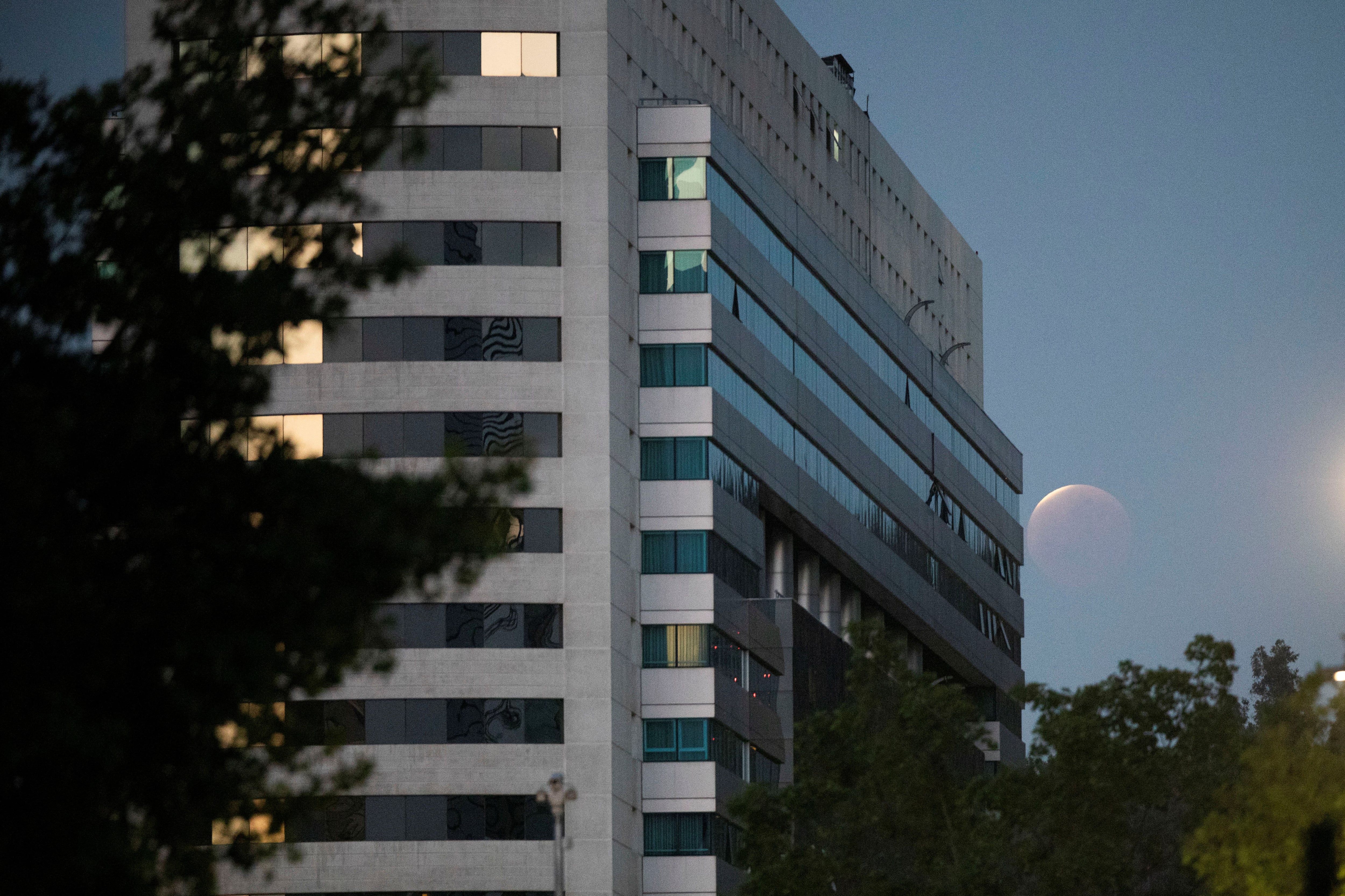 A partial lunar eclipse dubbed the 'blood moon' is seen next to the Gran Torre building in Santiago