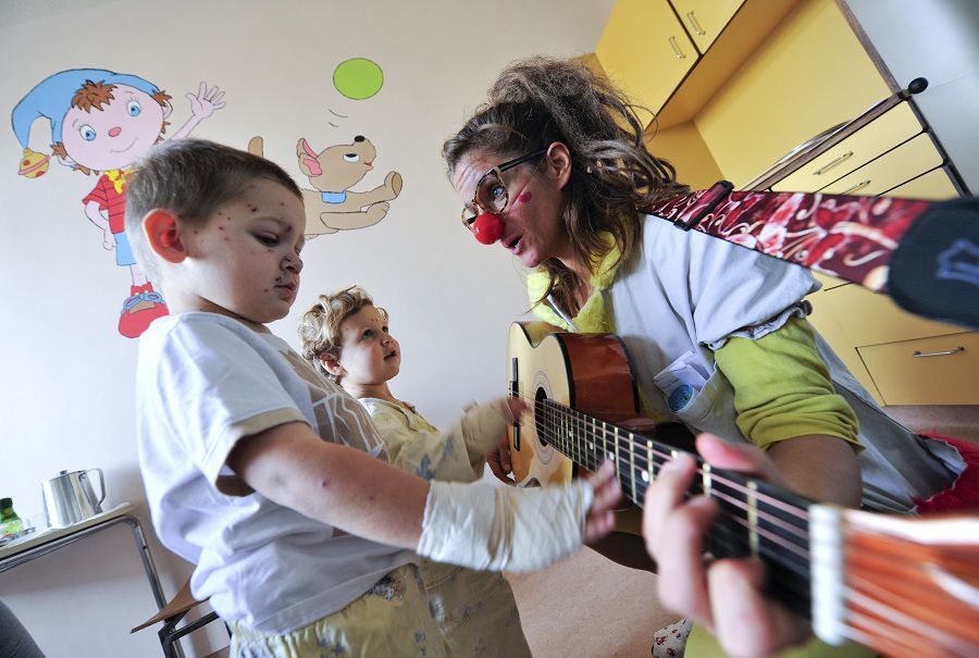 Member of Red Noses clown doctors sings to children in a clinic for infectious diseases in Ljubljana