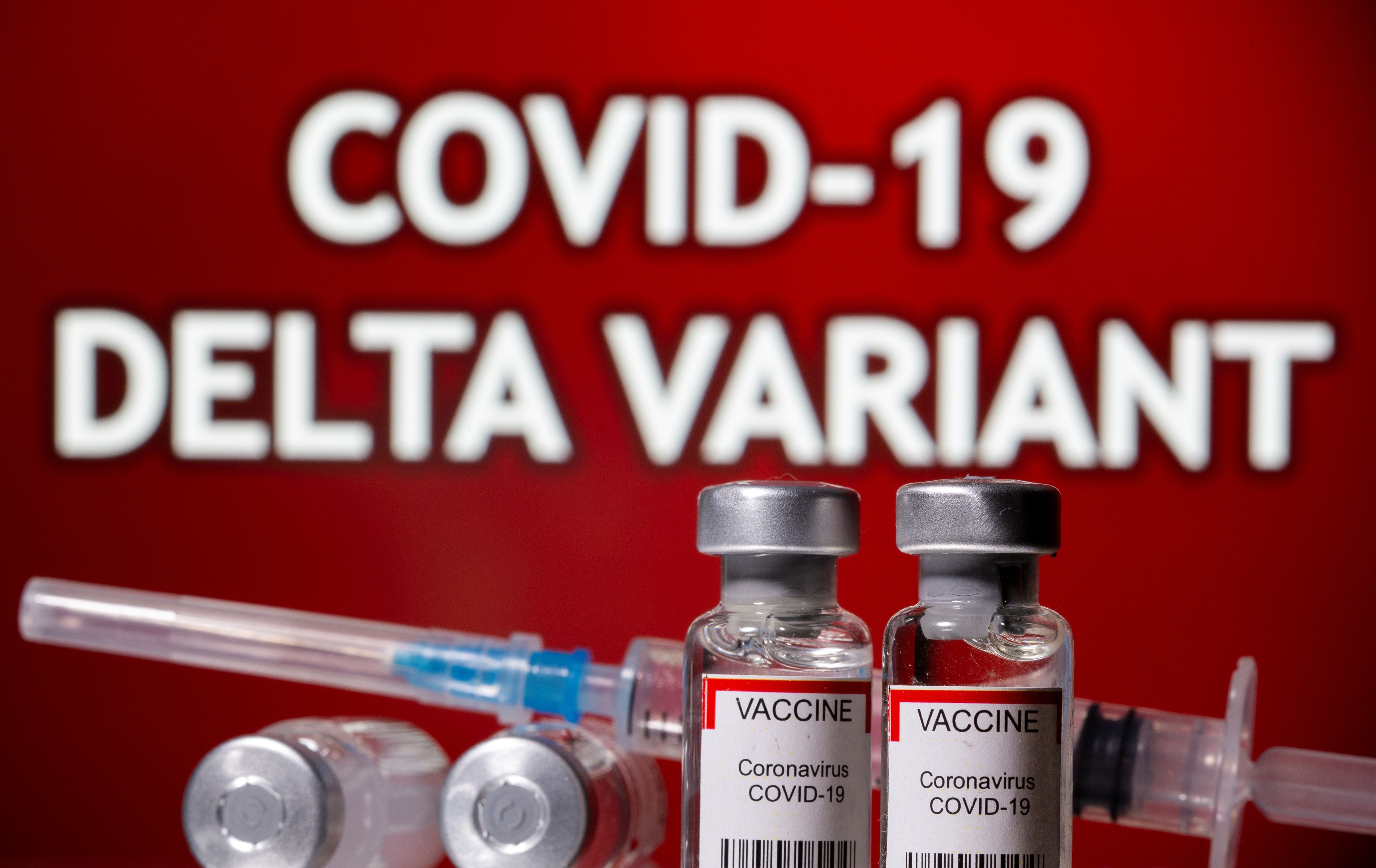 Illustration of vials labelled 'Vaccine coronavirus COVID-19' and a syringe in front of displayed words 'COVID-19 Delta variant'