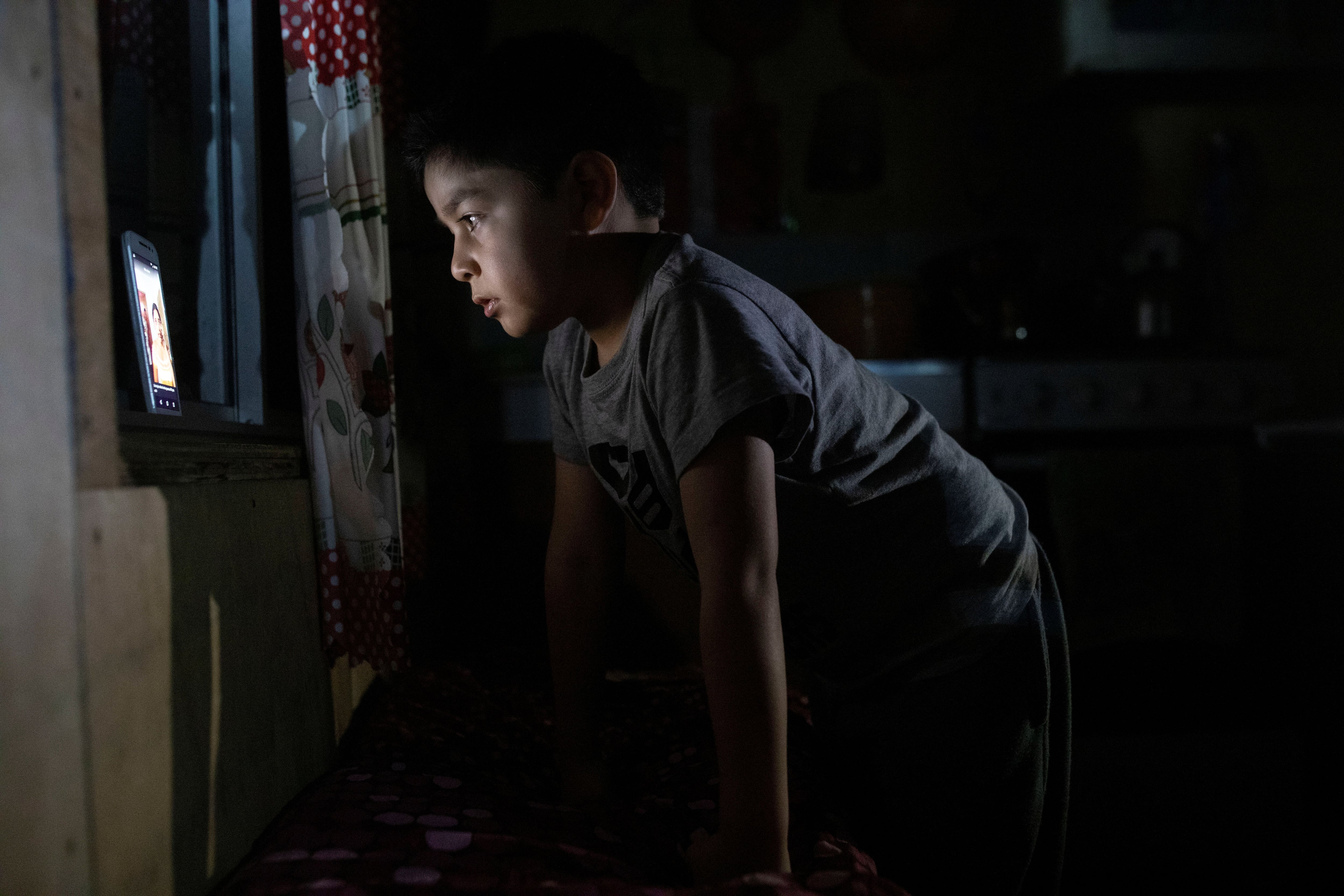 Diego Guerrero, de 7 años, observa un video en un teléfono móvil gracias a una débil señal que recibe en la localidad de Sotomó, en el extremo sur de Chile. REUTERS/Pablo Sanhueza