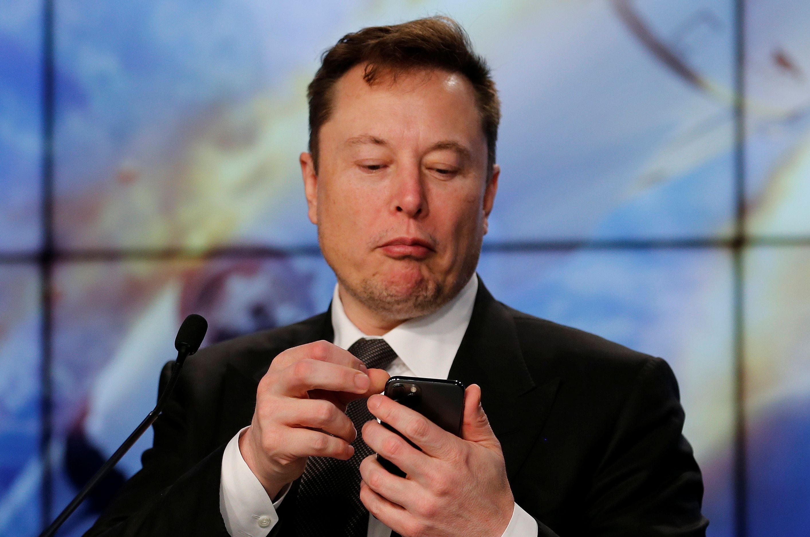 FILE PHOTO: SpaceX founder and chief engineer Elon Musk looks at his mobile phone during a post-launch news conference to discuss the  SpaceX Crew Dragon astronaut capsule in-flight abort test at the Kennedy Space Center