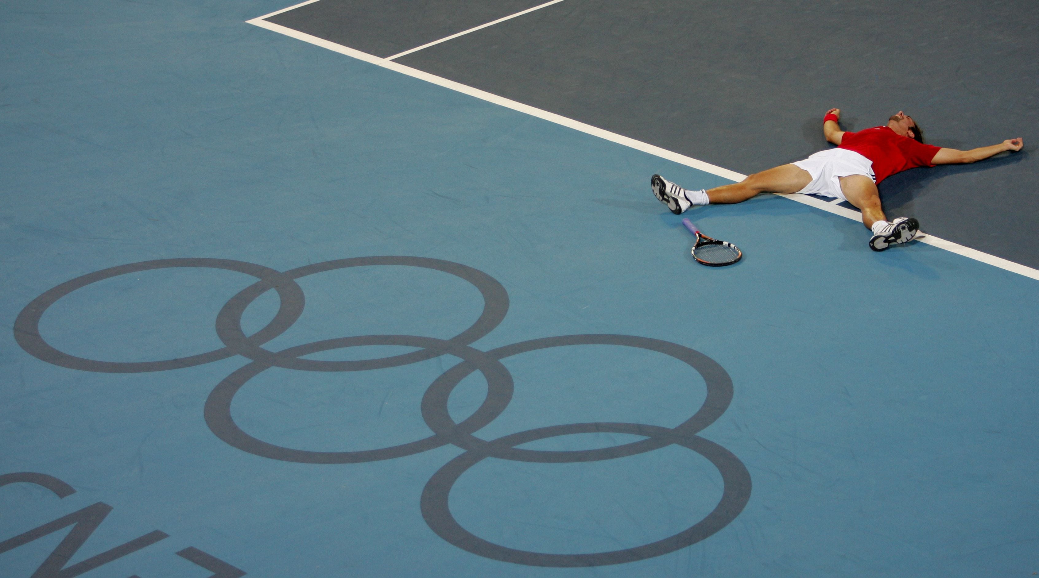 Chile's gold medallist Nicolas Massu lies on the tennis court after men's singles final tennis match ...