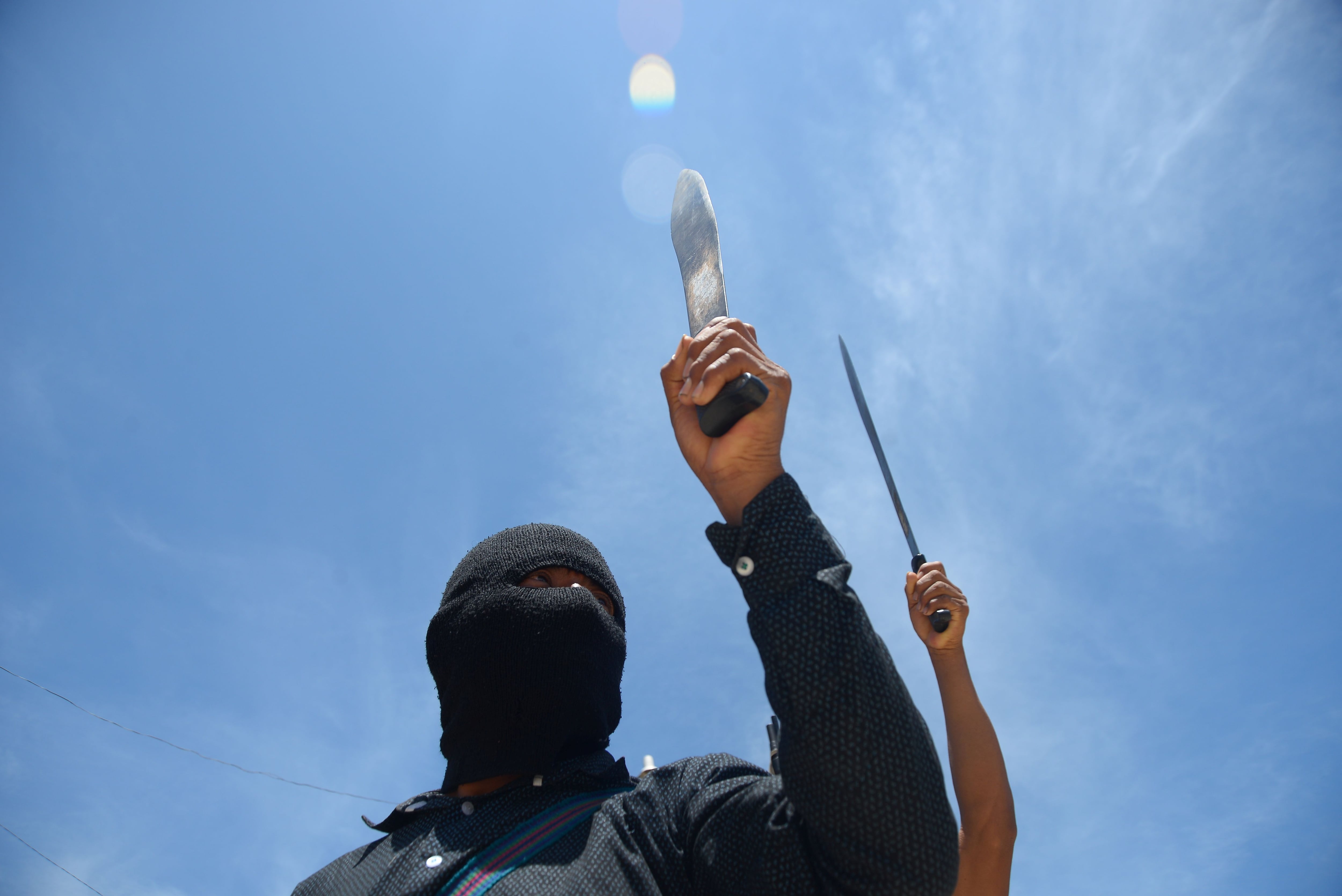 Vigilantes of El Machete as they call themselves, an armed group made up mostly of indigenous people to defend themselves against drug cartels, hold up their machetes during an assembly with indigenous communities, in Pantelho