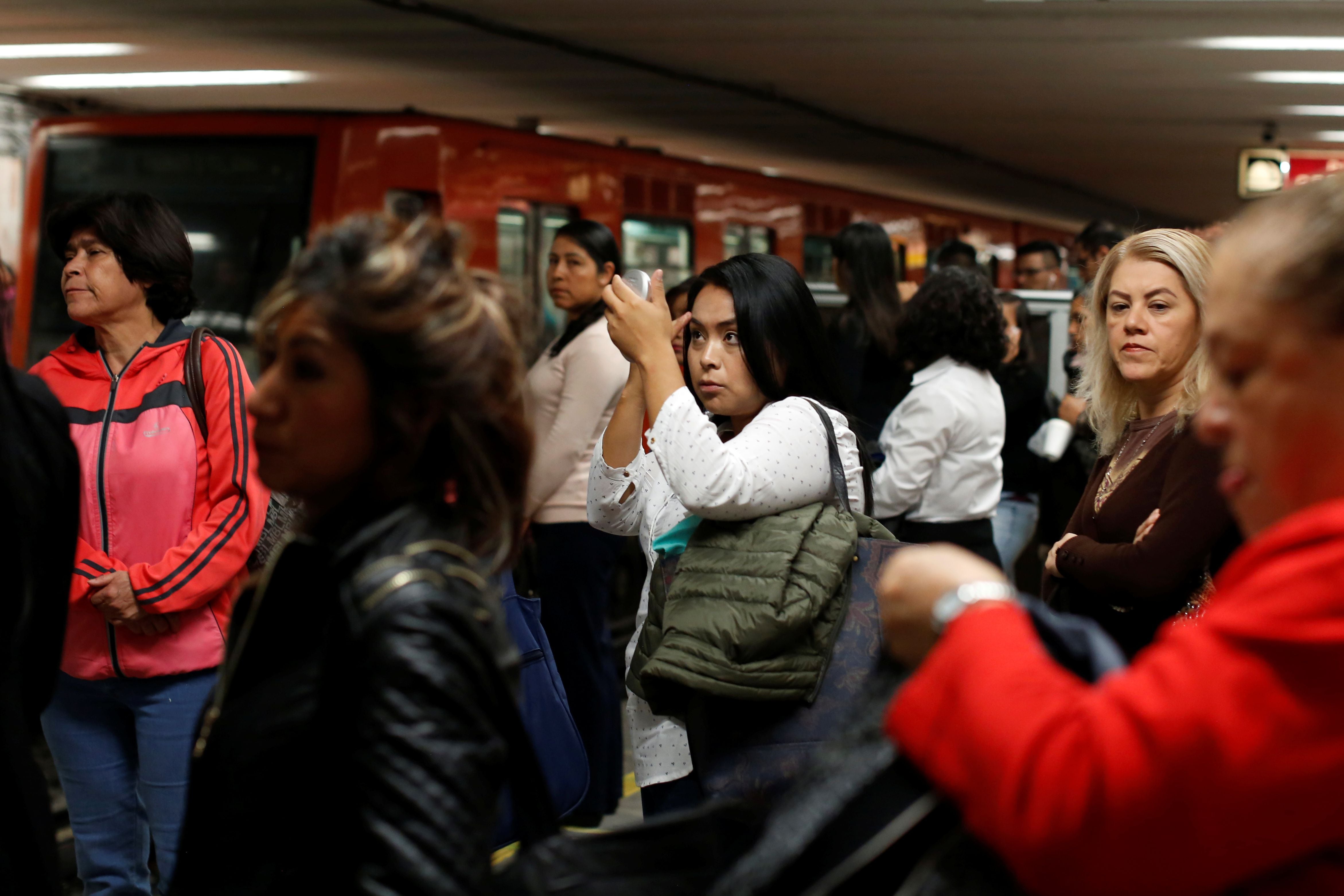 Woman puts on makeup as she waits to board the Women-Only passenger carriages at a metro station in Mexico City