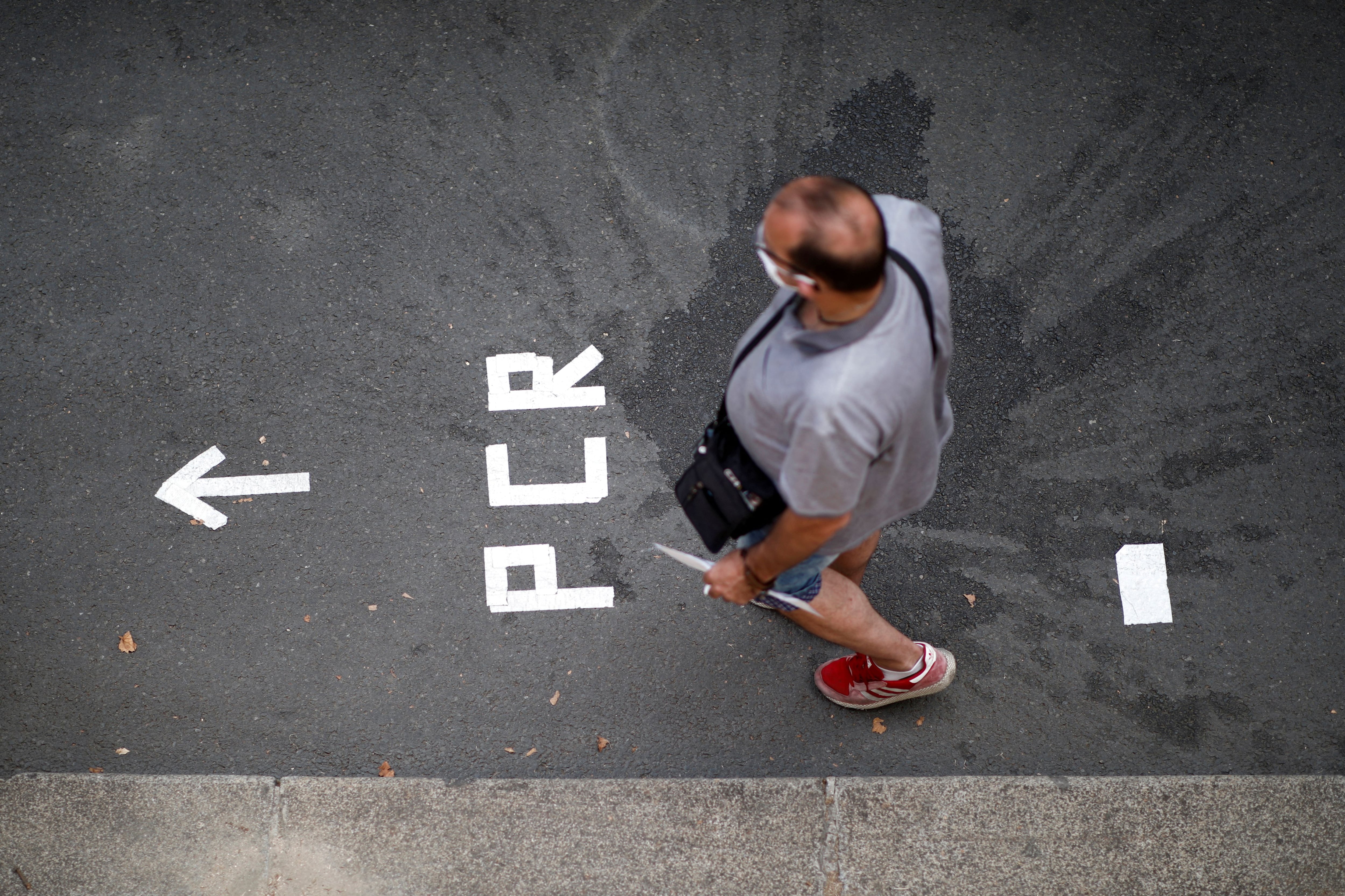 FILE PHOTO: A man queues to take a PCR test for the coronavirus disease (COVID-19) in Paris