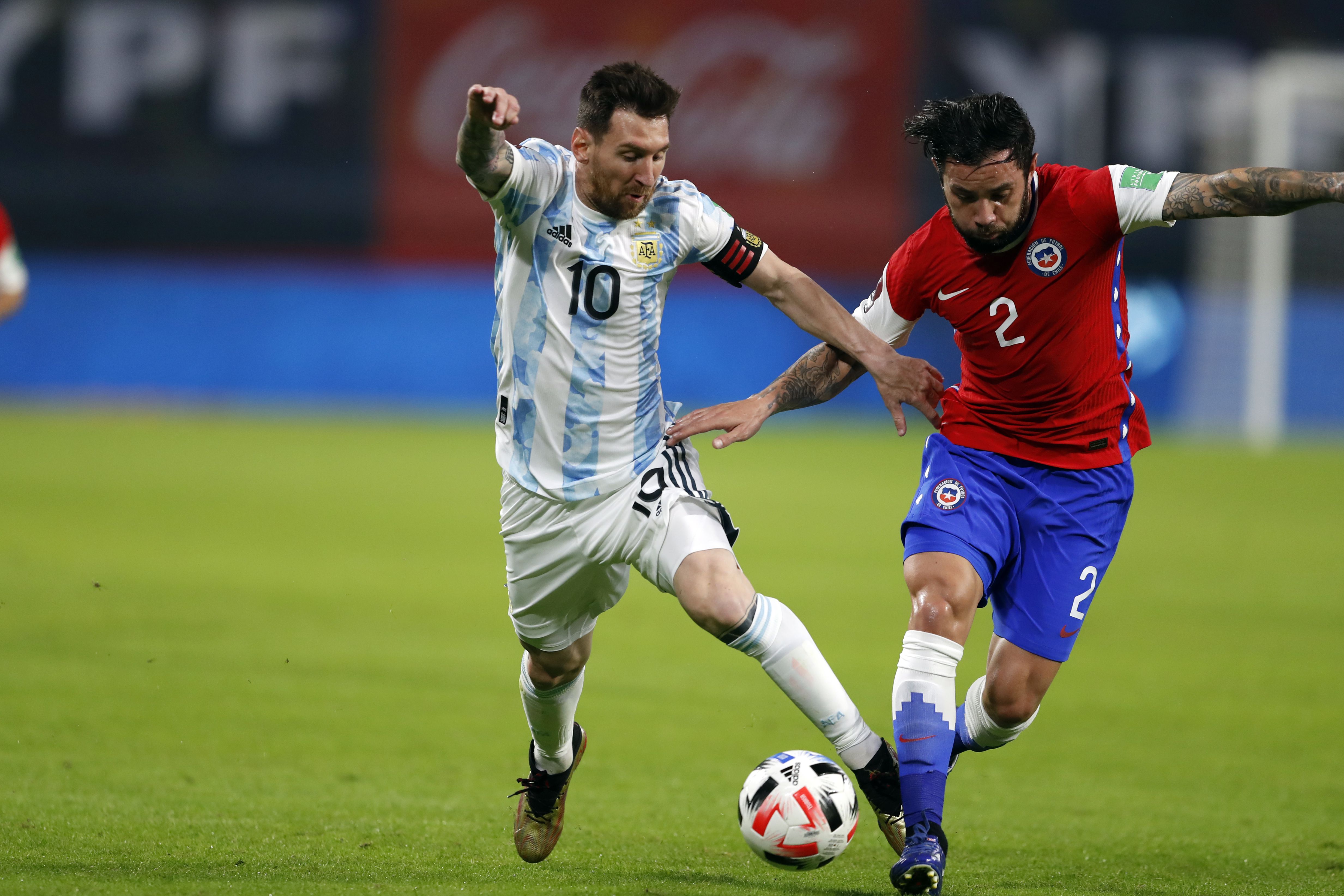 Eugenio Mena marca a Lionel Messi, durante un partido de las Eliminatorias para el Mundial de Qatar 2022.