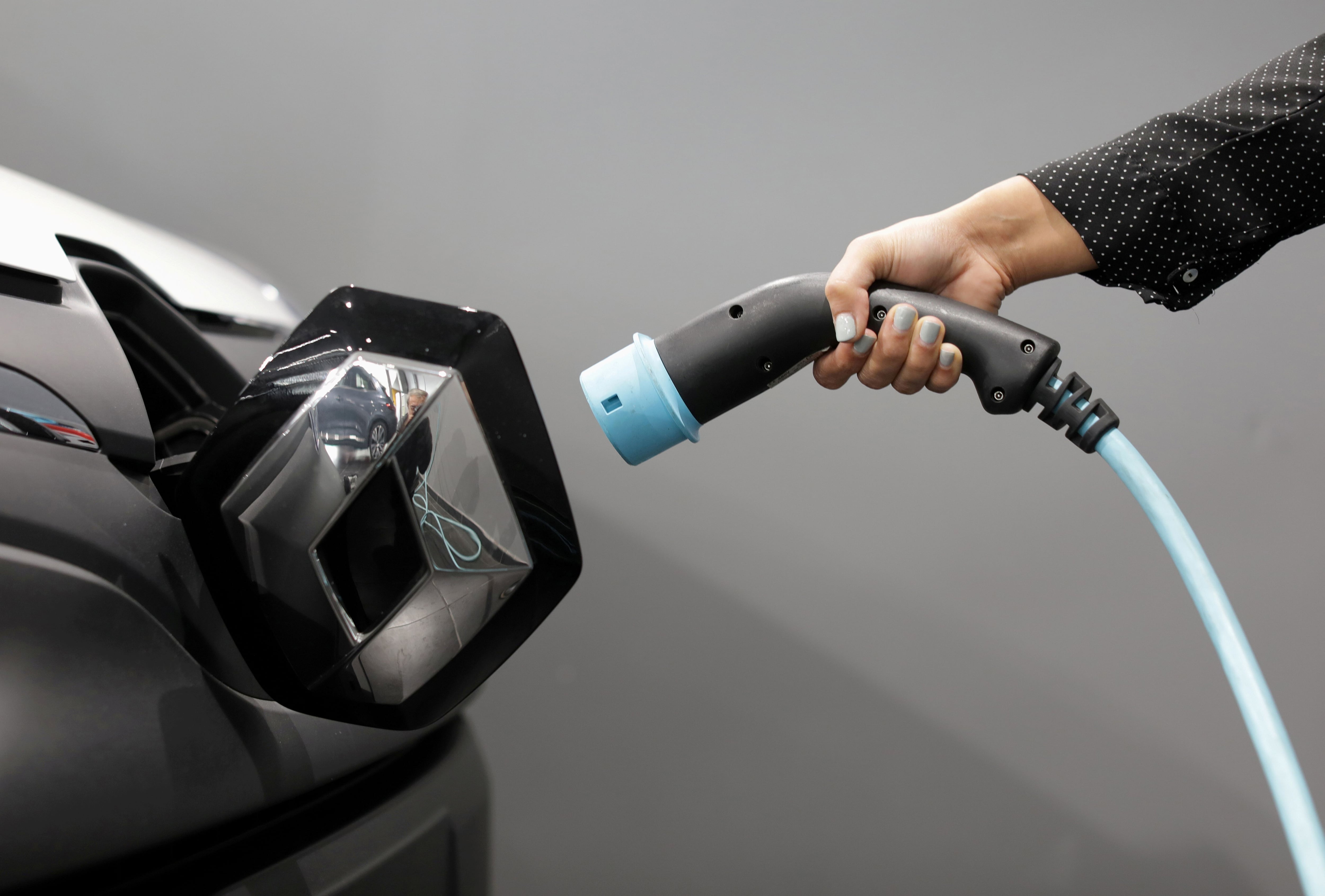 FILE PHOTO: A woman holds a cable to charge a Renault utility vehicle at a dealership in France