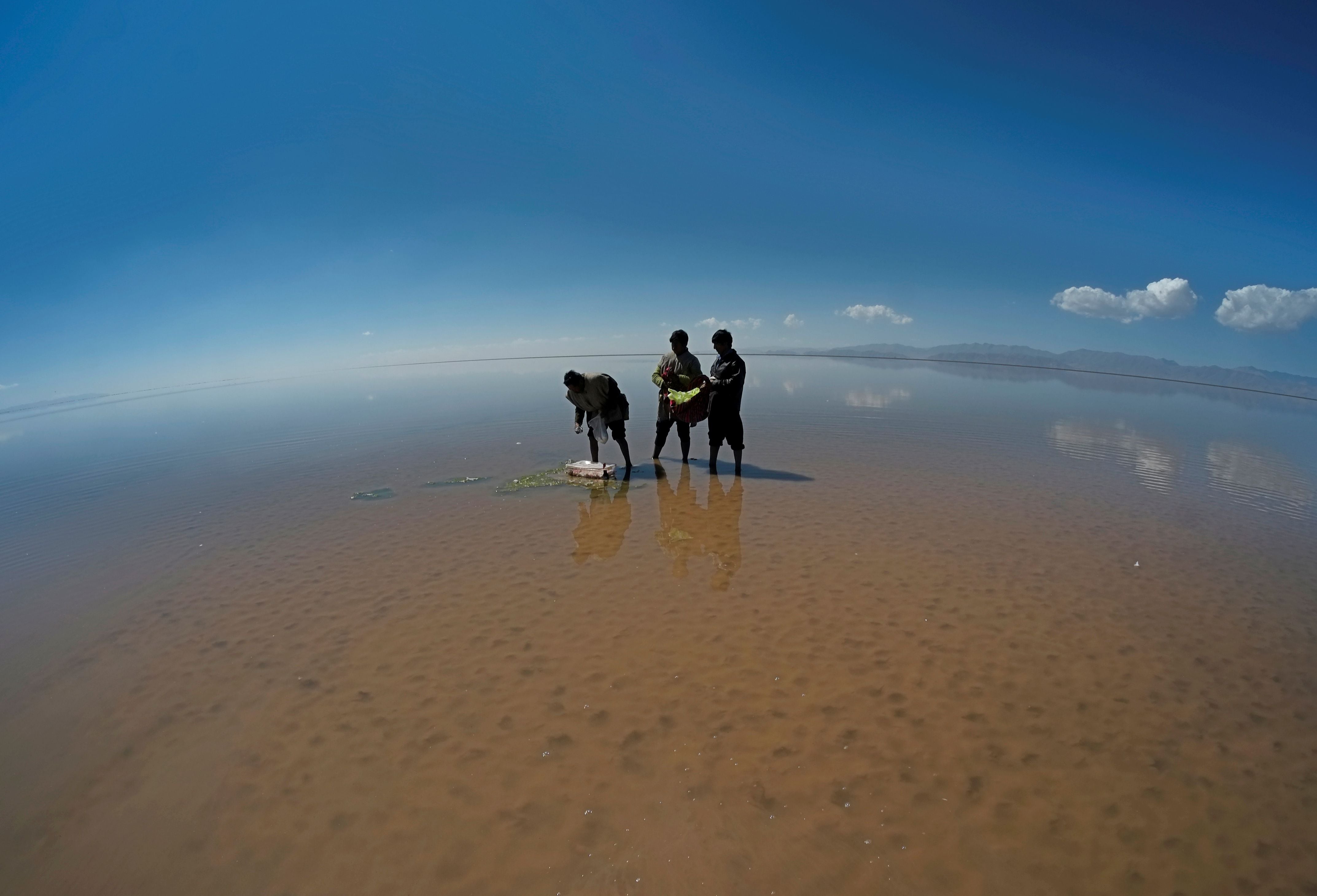 Urus Muratos men participate in an offering to Kota Mama (Mother Water) on the dried lake Poopo affected by climate change, in the Oruro Department