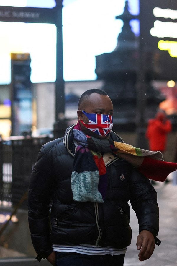 FILE PHOTO: A person wearing a protective face mask walks through Piccadilly Circus, amid the coronavirus disease (COVID-19) outbreak, in central London