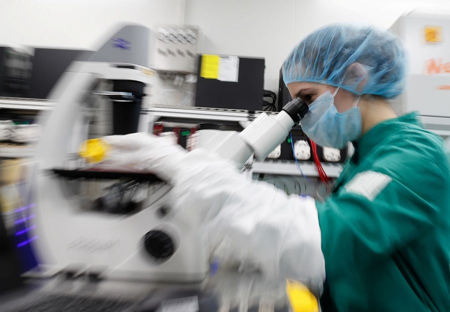 A scientist examines COVID-19 infected cells under a microscope during research for a vaccine against the coronavirus disease at a laboratory in Saint Petersburg