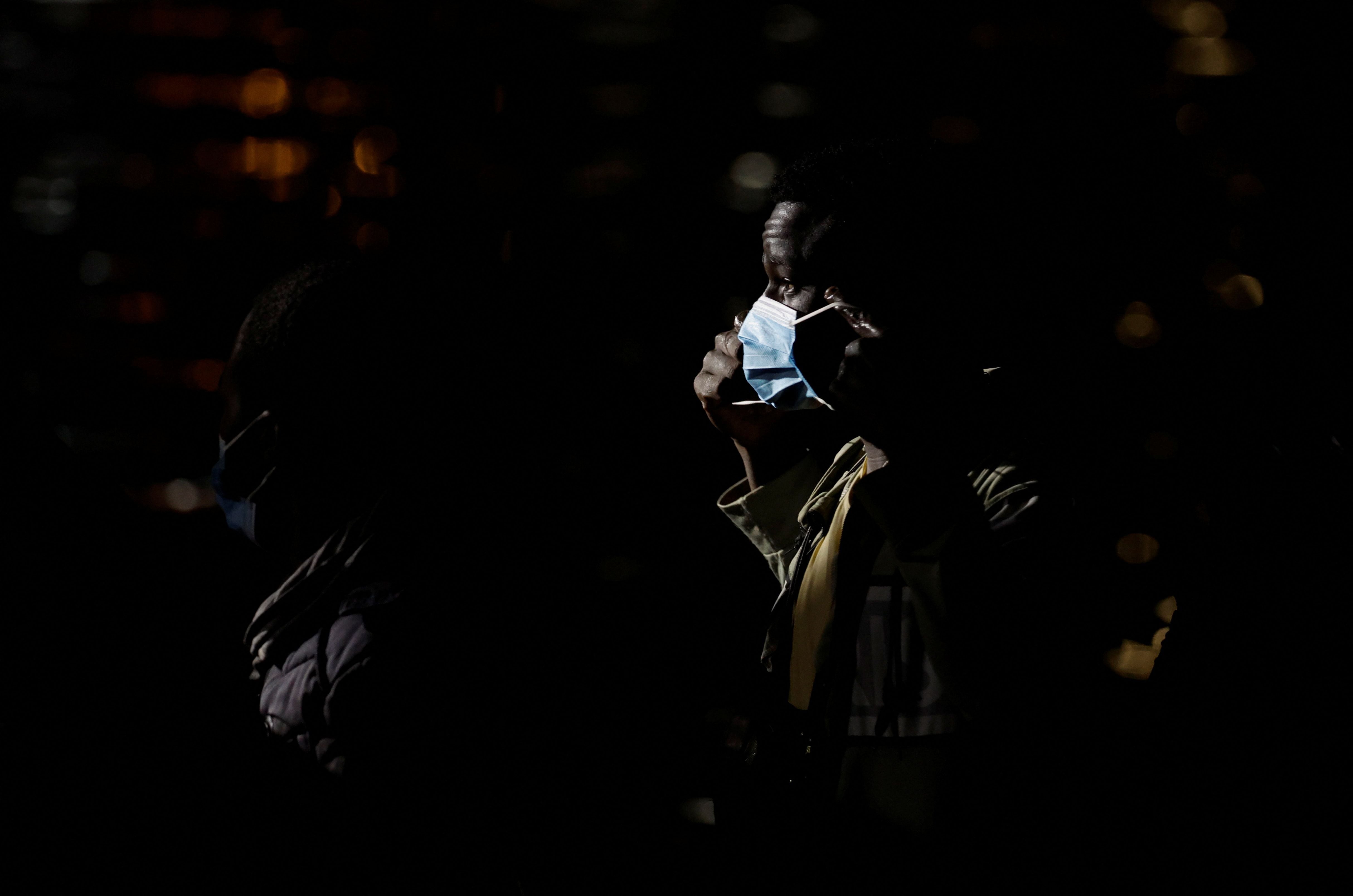 A migrant puts a face mask on before disembark from a Spanish coast guard vessel, in the port of Arguineguin