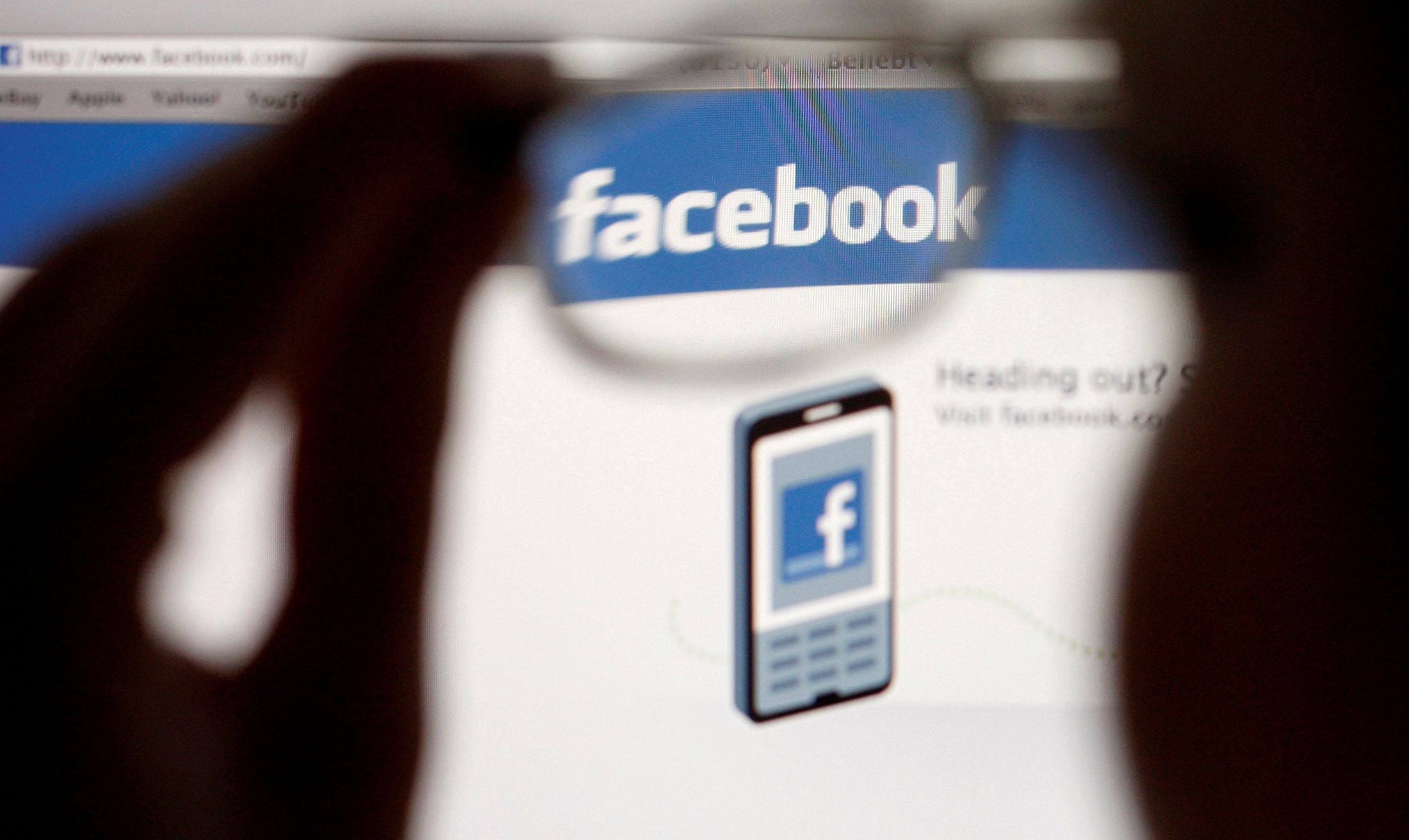 FILE PHOTO: In this photo illustration, a Facebook logo on a computer screen is seen through glasses held by a woman in Bern