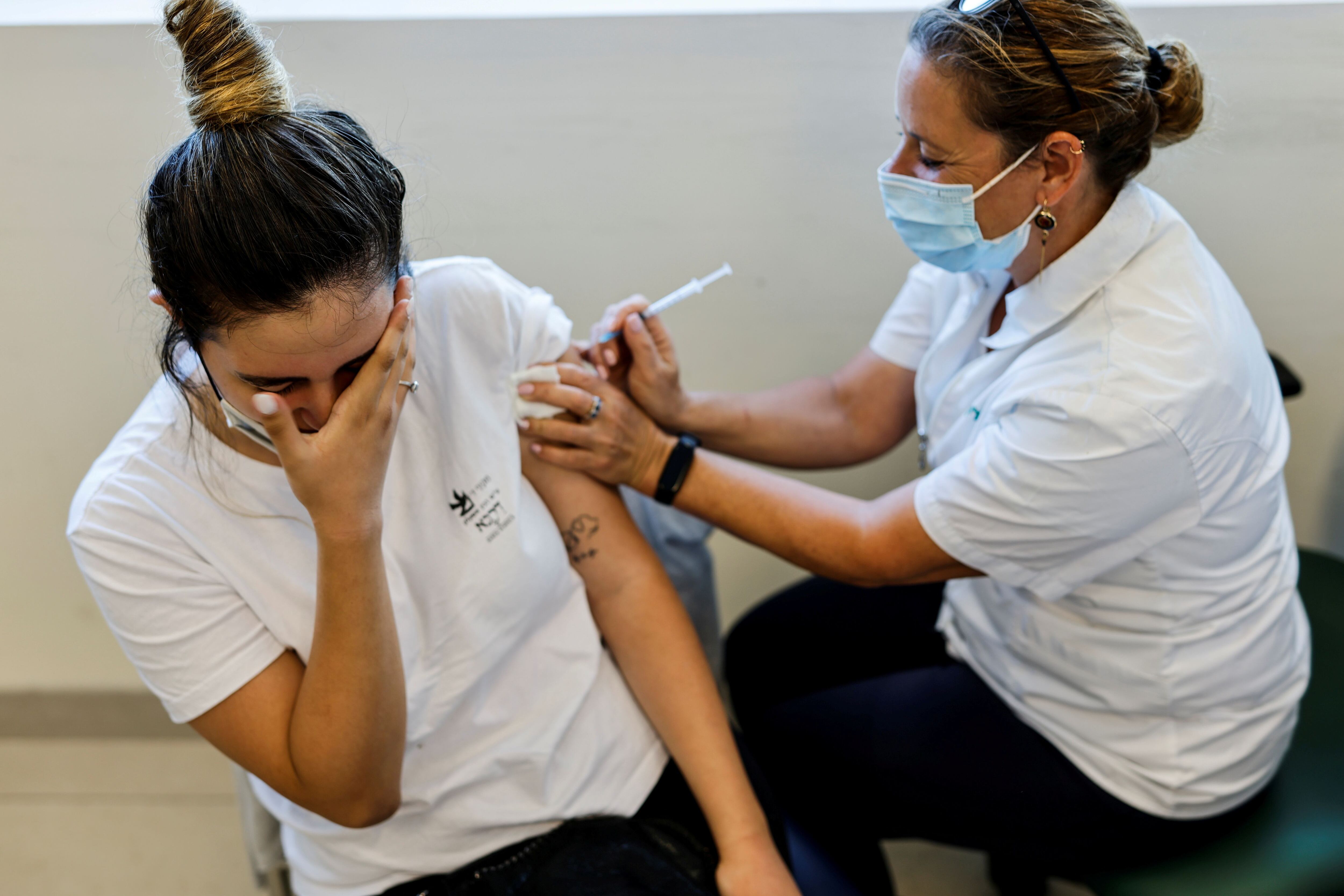 FILE PHOTO: A teenager receives a dose of a vaccine against the coronavirus disease (COVID-19) after Israel approved the usage of the vaccine for youngsters aged 12-15, at a Clalit healthcare maintenance organisation in Ashkelon