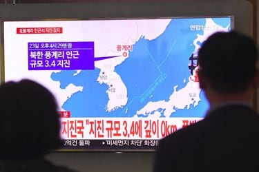 People watch a television news screen showing a map of the epicenter