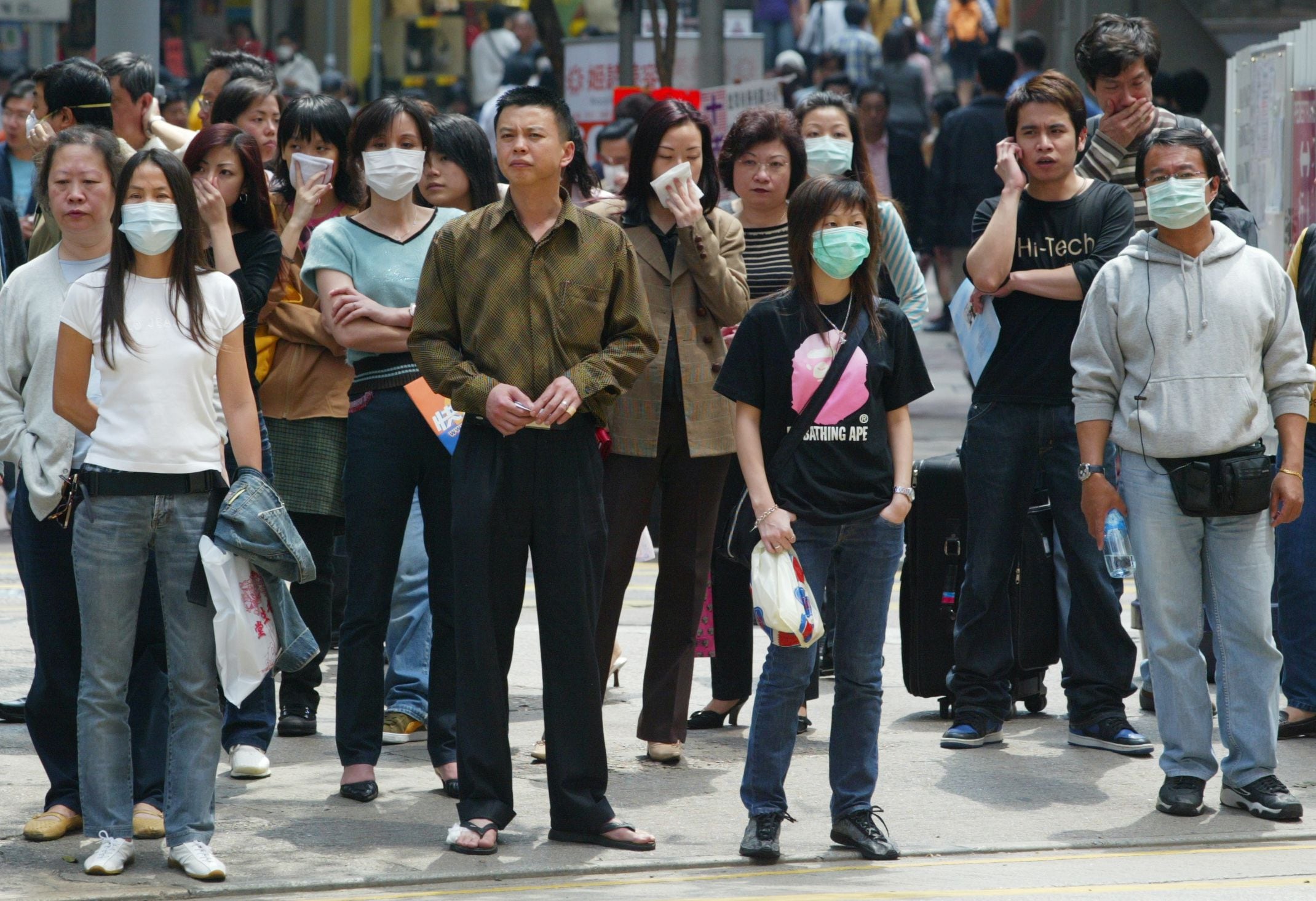 PEDESTRIANS WEARING PROTECTIVE MASKS WAIT TO CROSS A STREET IN HONG
KONG.