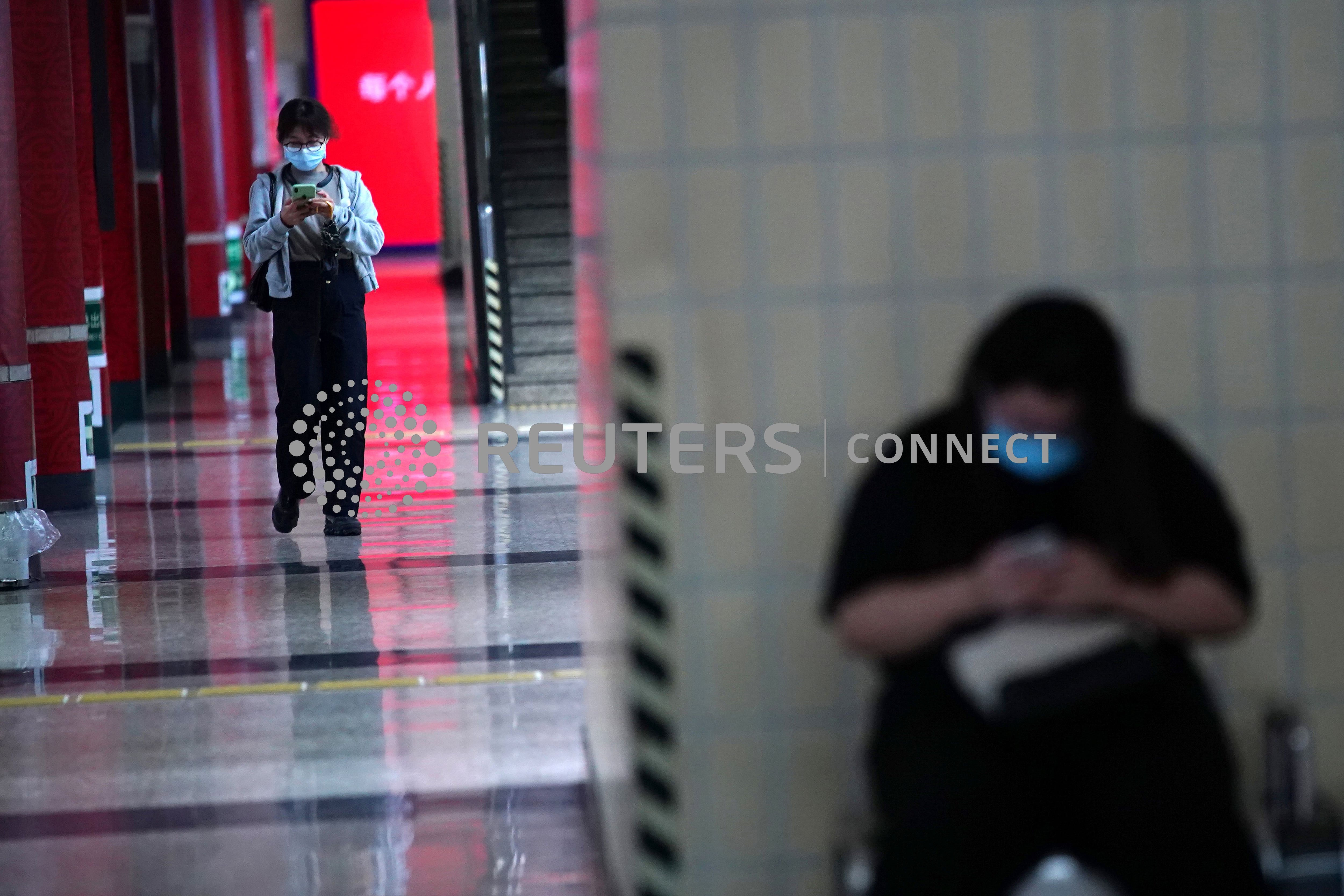 Pasajeros con mascarillas utilizan sus teléfonos en una estación de metro de Pekín, China