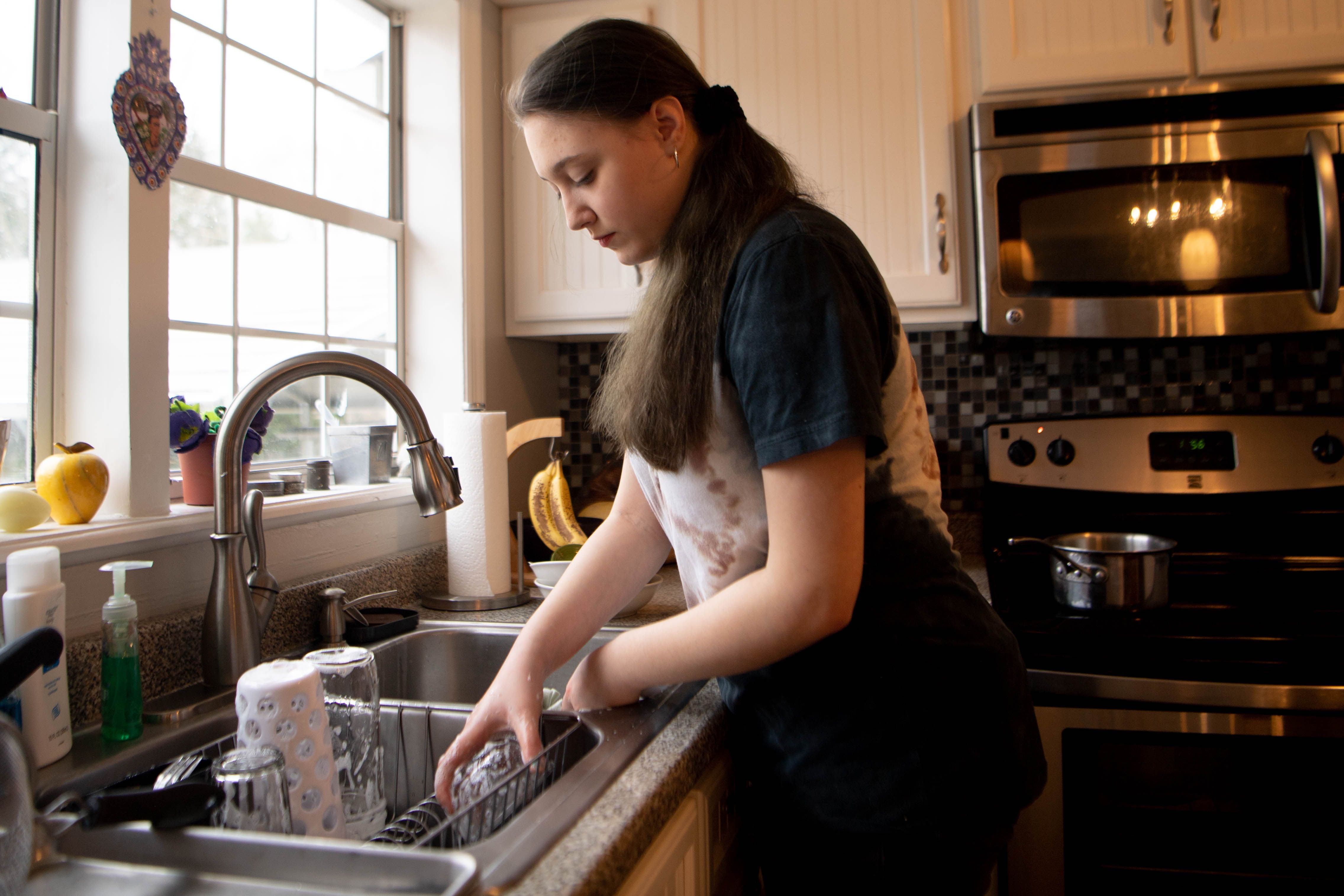 Jordann Scott, 18, washes the dishes and boils water for pasta in her Chattanooga home Dec. 9, 2019. Scott is one of about 5,000