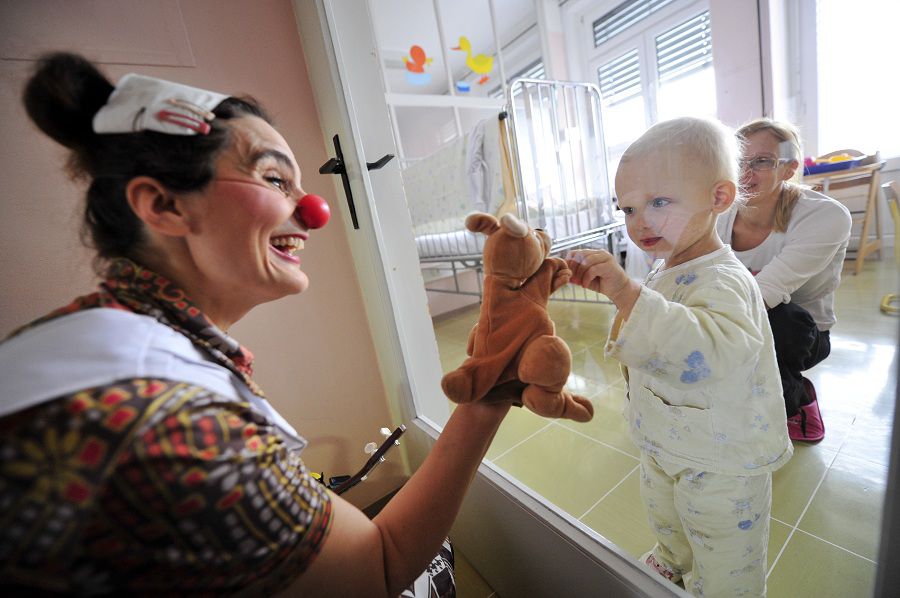 Member of Red Noses clown doctors plays with children in a clinic for infectious diseases in Ljubljana